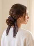 Woman with a low bun tied with the Plum Tartan Moons chiffon square scarf as a hair bow