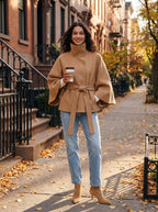 Woman wearing the City Muse camel cape coat on a New York brownstone street in autumn, holding a coffee