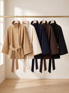 City Muse belted cape coat in all five colors on a rail: camel, cream, navy, chocolate and black