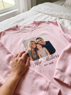 Close-up of a light pink custom photo sweatshirt showing the family photo print with the name The Millers and EST. 2018
