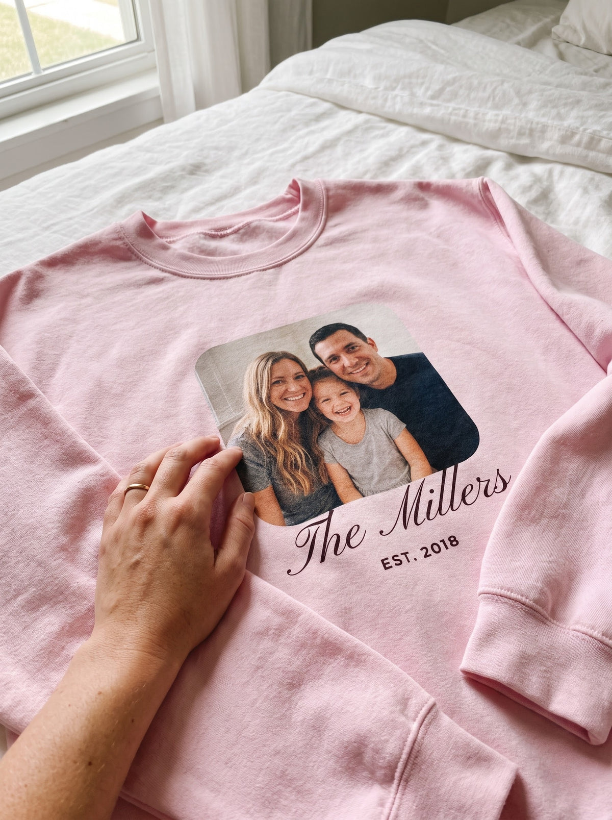 Close-up of a light pink custom photo sweatshirt showing the family photo print with the name The Millers and EST. 2018