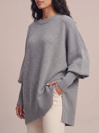 Close-up of the gray oversized sweater showing the batwing sleeve, long ribbed cuff and ribbed high-low hem with side slit