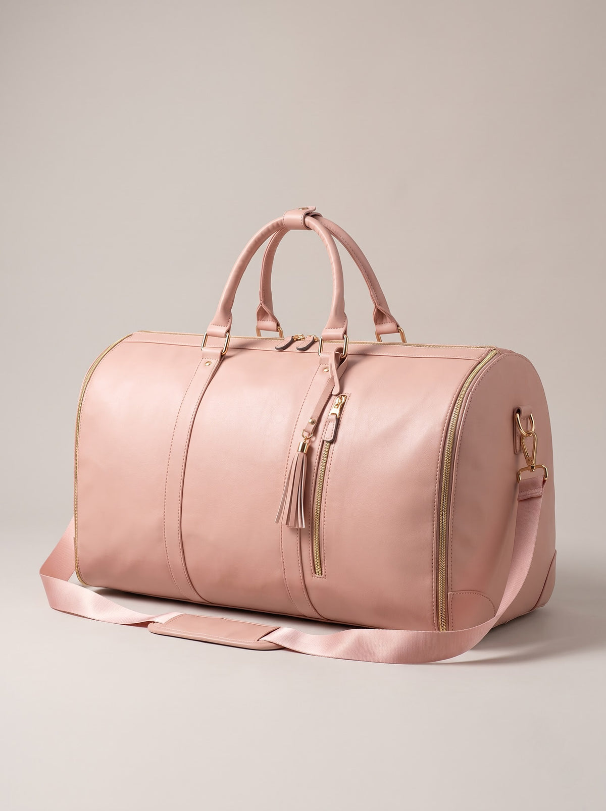 Getaway foldable garment duffle bag in blush pink faux leather with gold zippers and shoulder strap