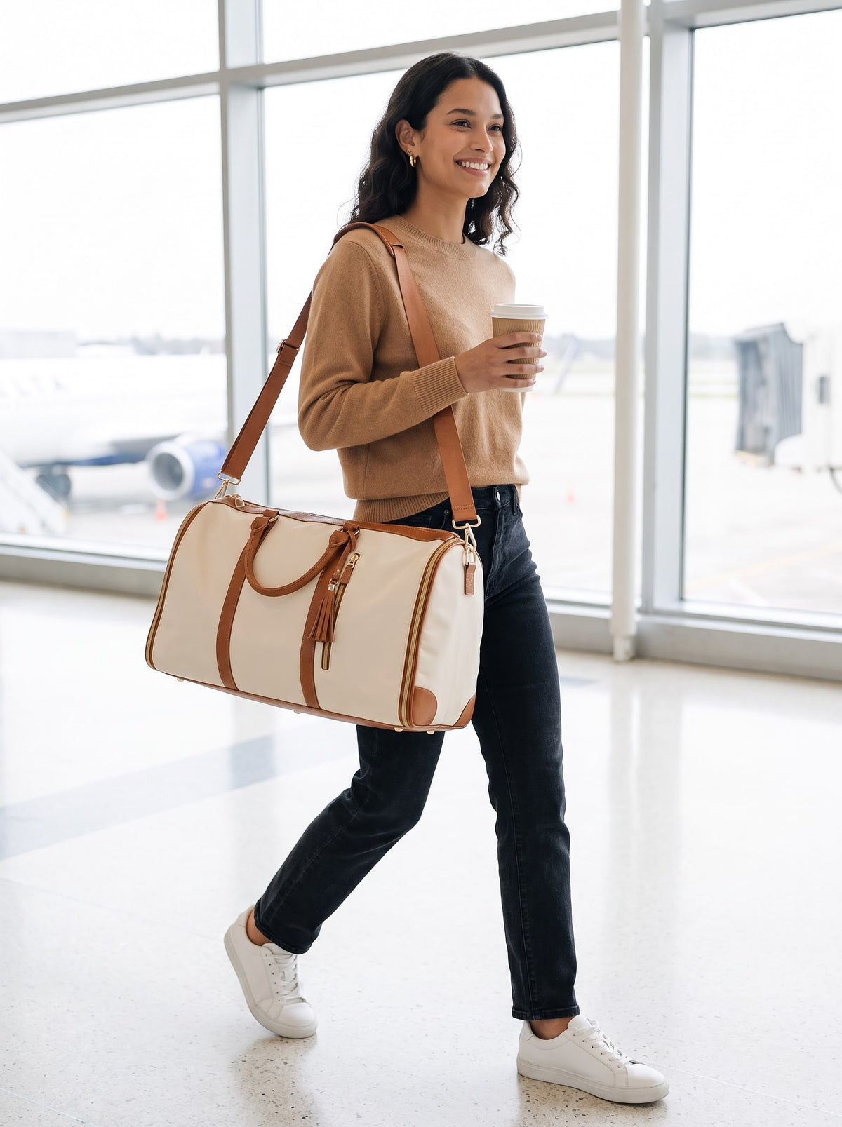 Woman carrying the cream and tan Getaway garment duffle bag on her shoulder through an airport