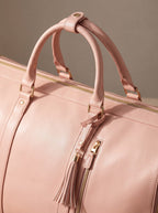 Close-up of the pink duffle bag top handles, gold zipper and tassel pull