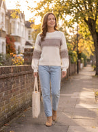 Woman walking down an autumn street in the cream and taupe rib knit sweater, light jeans and a canvas tote