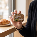 Leopard print personalized AirPods Pro 3 case with a pet photo window and name plate, held by a café window