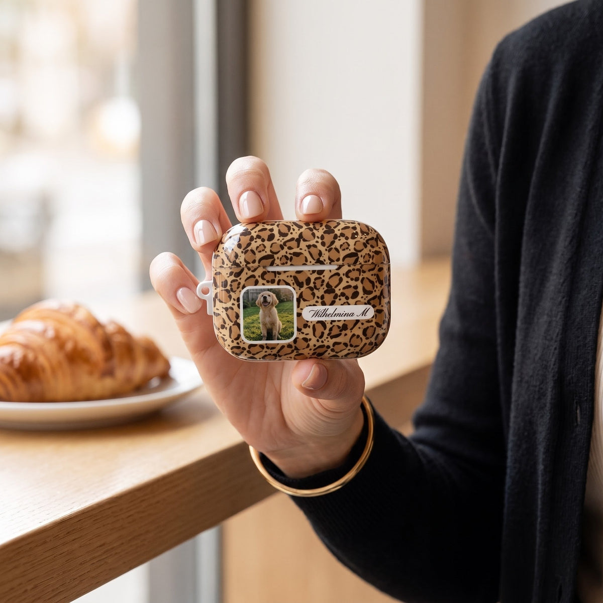 Leopard print personalized AirPods Pro 3 case with a pet photo window and name plate, held by a café window
