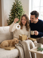 Couple unwrapping a personalized dog photo ornament from its gold gift box on Christmas morning