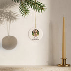 Round custom puppy photo ornament hanging from a fir sprig beside a candle