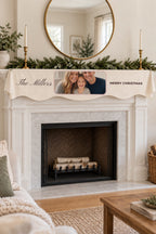 Cream wavy-hem mantel scarf printed with a family photo, The Millers and Merry Christmas, on a white mantel above an unlit fireplace