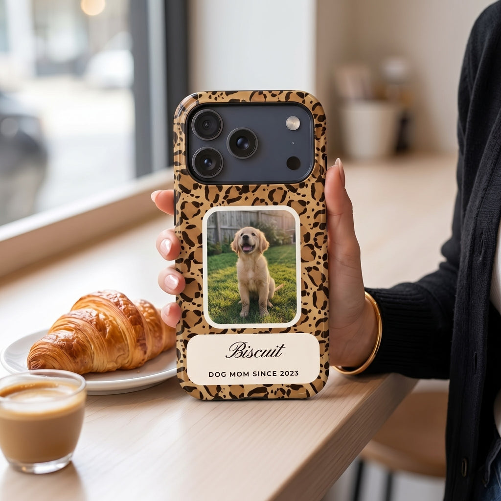 Framed design phone case: leopard pattern with a puppy photo window and the name Biscuit, standing on a café counter