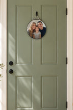 Round wood sign printed with a family photo, The Parkers and Est. 2015, hung by a cream cord on a sage front door