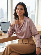 Woman wearing the lotus pink Quiet Luxe satin blouse at an office desk