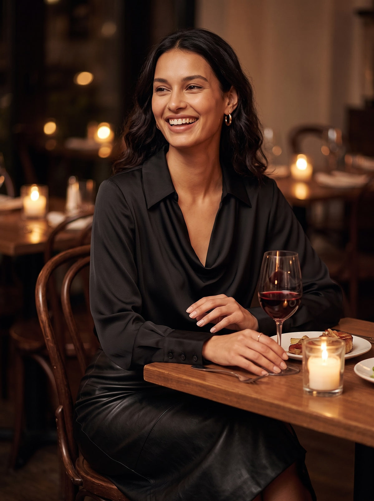 Woman in the black Quiet Luxe satin blouse at a candlelit dinner