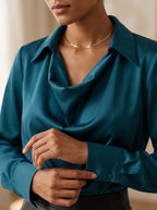Close-up of the shirt collar, draped cowl neckline and buttoned cuff of the peacock blue Quiet Luxe blouse