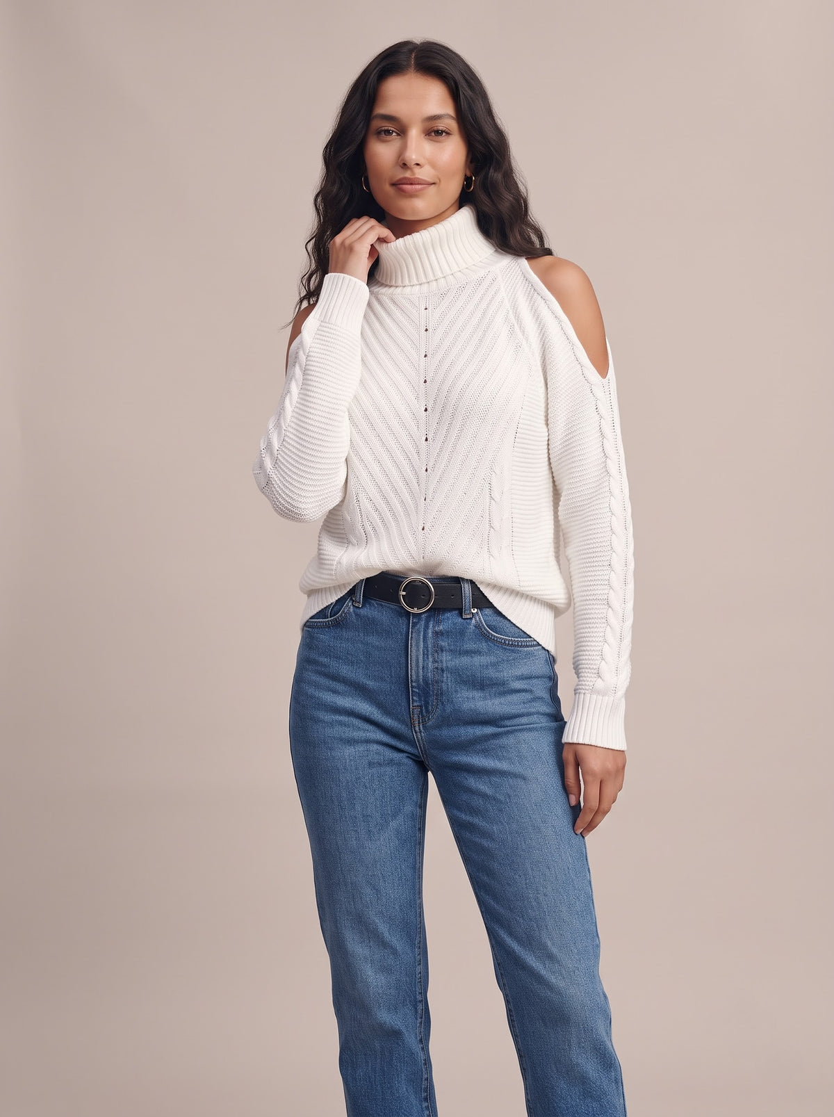 Soft Spell cold-shoulder turtleneck knit sweater in white, worn with blue straight jeans and a black belt, studio photo