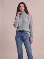 Soft Spell cold-shoulder turtleneck knit sweater in gray, front view with blue jeans, studio photo
