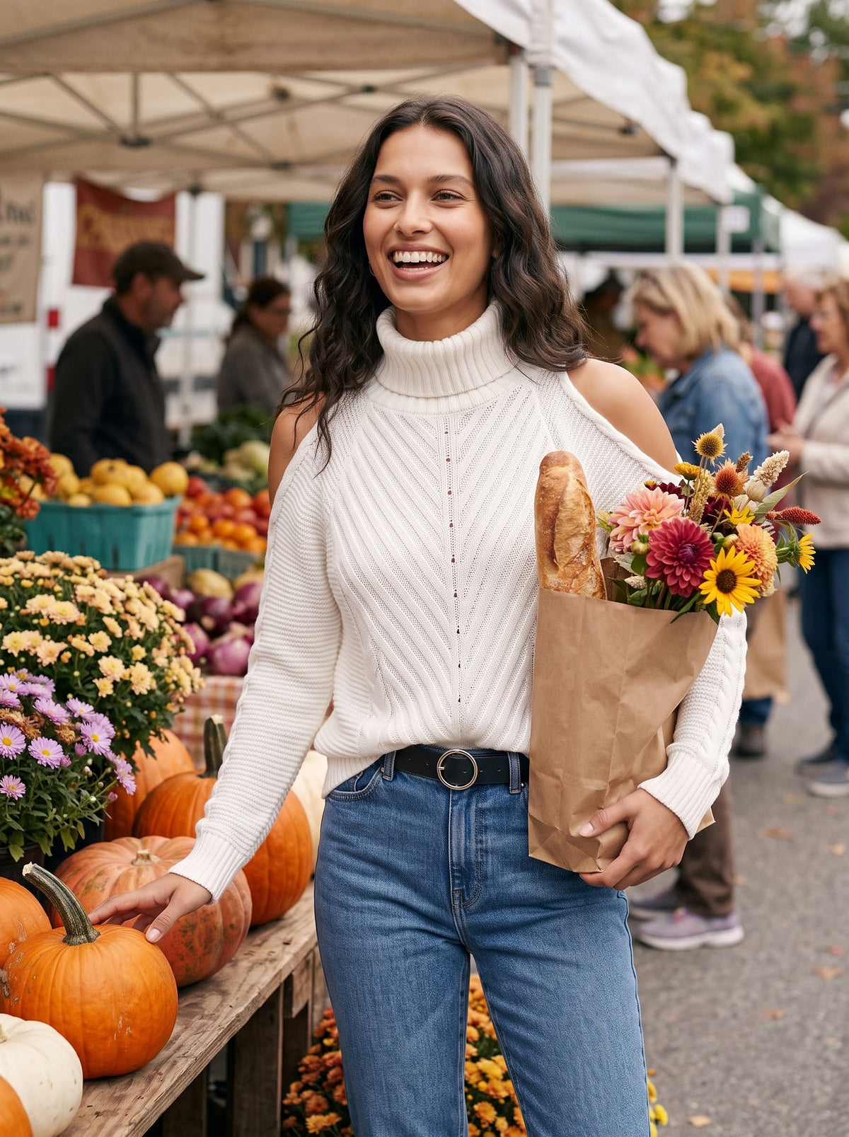 Woman at an autumn farmers market wearing the white cold-shoulder turtleneck sweater with jeans, holding flowers and a baguette