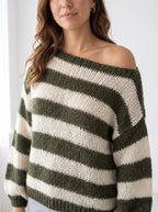 Close-up of the loose-gauge open knit and wide boat neckline worn off the shoulder, military green stripes