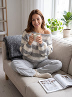 Woman relaxing on a sofa with coffee in the gray and cream striped knit sweater