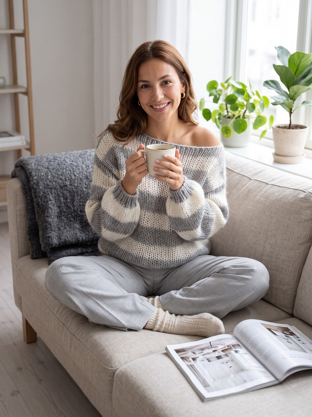 Woman relaxing on a sofa with coffee in the gray and cream striped knit sweater